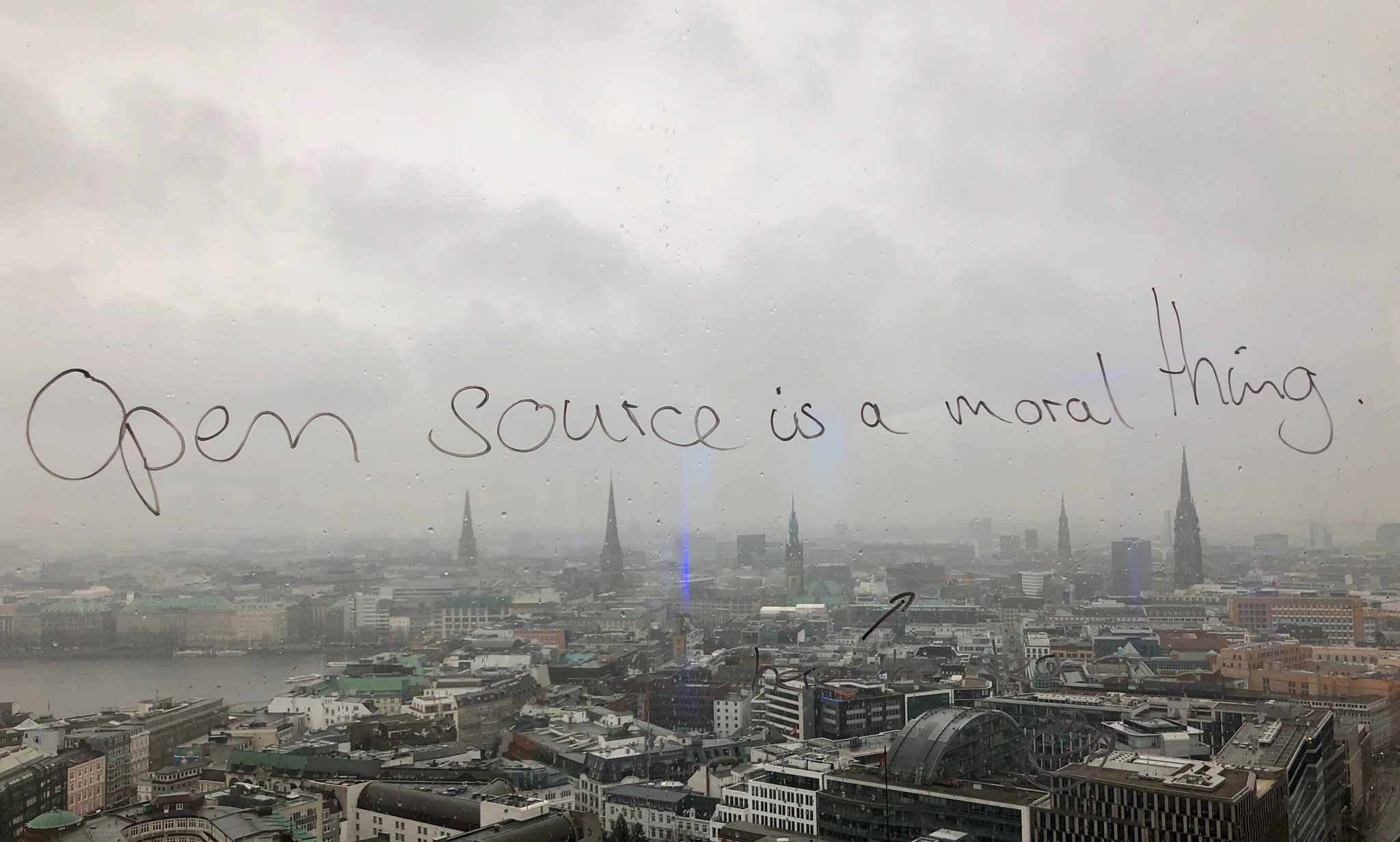 Skyline of Hamburg, with "Open source is a moral thing" written on the window pane.